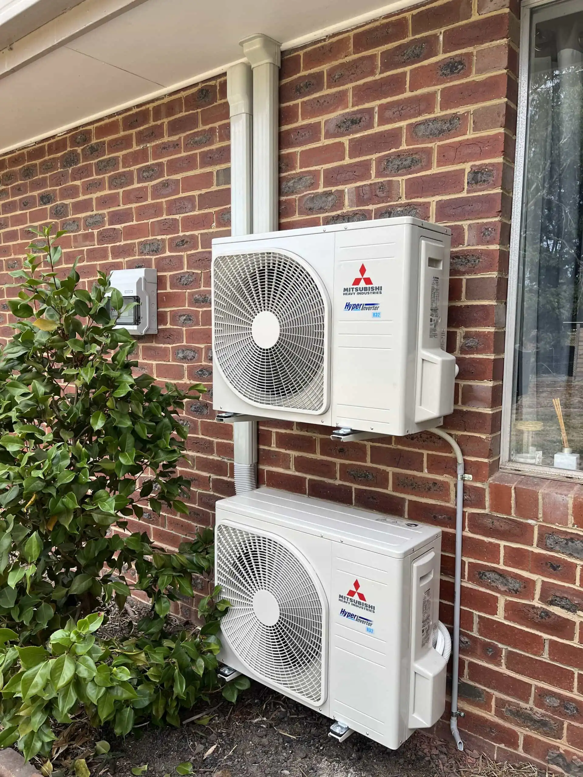 Split-system air conditioning condensers installed on a brick wall